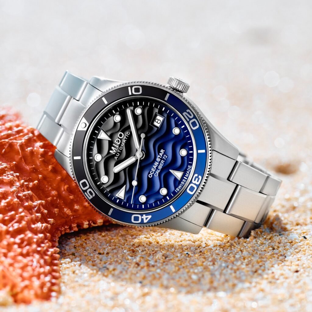 Reloj Mido Ocean Star 39 a un lado de una estrella de mar en la playa.