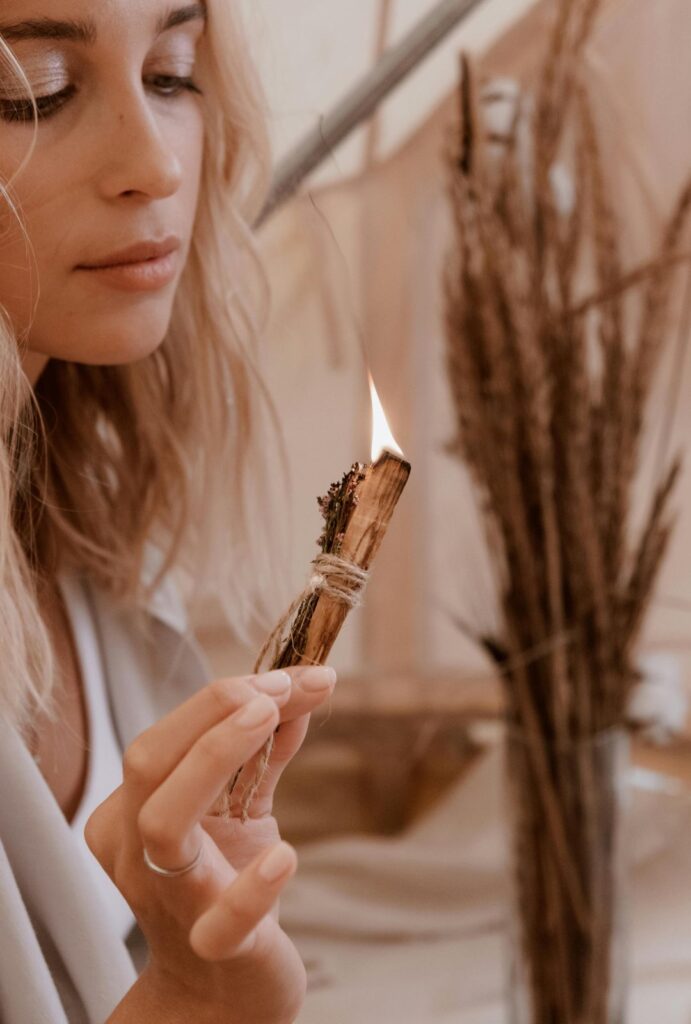 Chica haciendo una limpieza energética con un palo santo y sahumito.