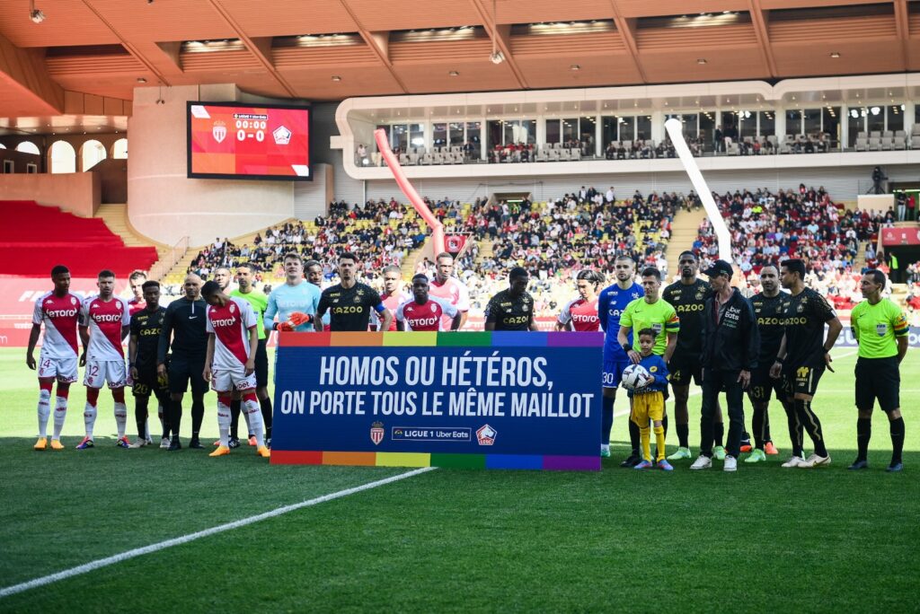 Jugadores del AS Monaco y del Lille Olympique Sporting Club (LOSC) posan con una pancarta con los colores del arcoíris LGBTQIA+ que dice 'Gay o heterosexual, todos llevamos la misma camiseta'